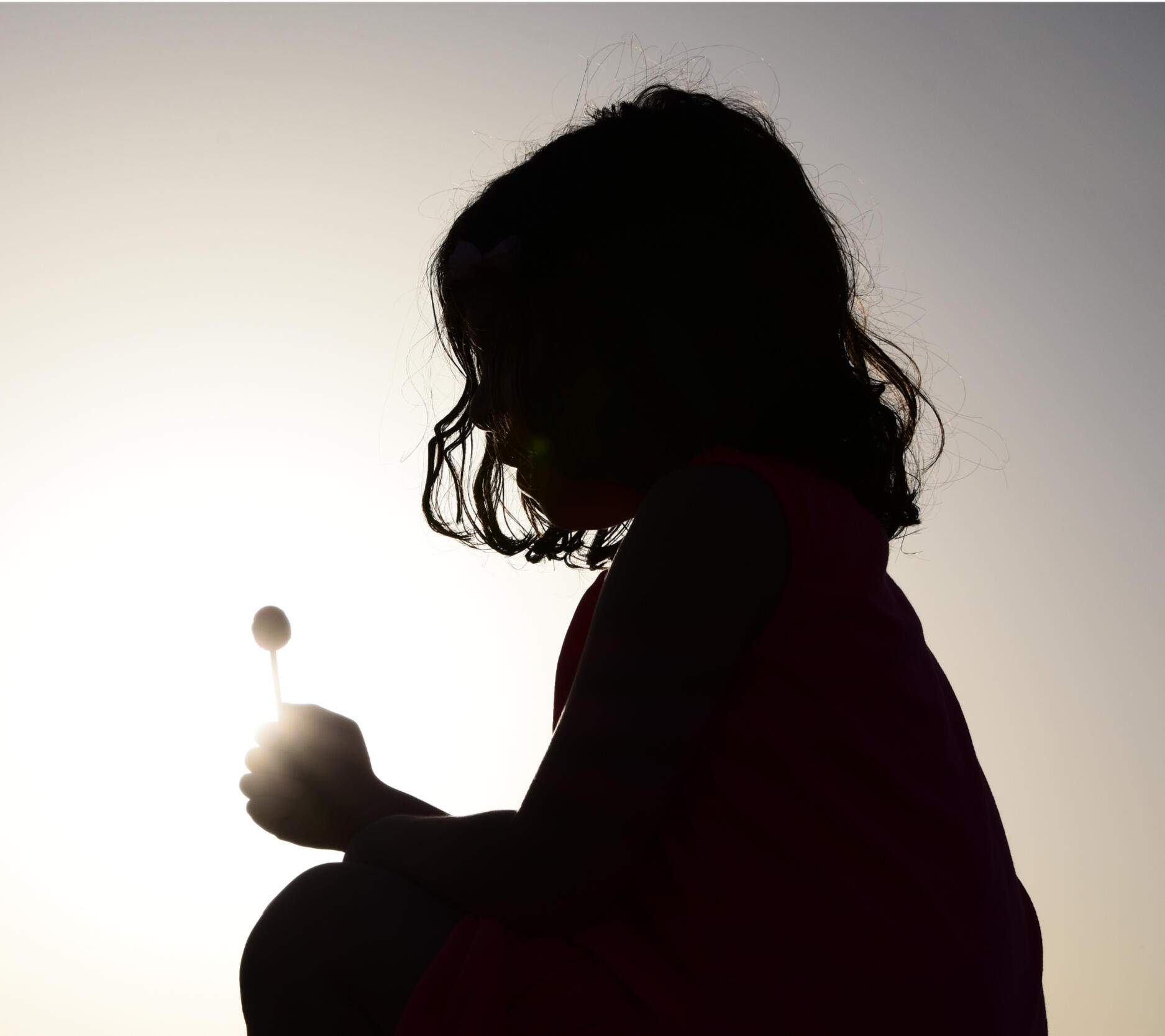 Child Reflecting with Lollipop – Somatic Safety and Nervous System Calm meditation Silhouette of a young child holding a lollipop, symbolizing innocence, safety, and somatic calm through embodied healing.